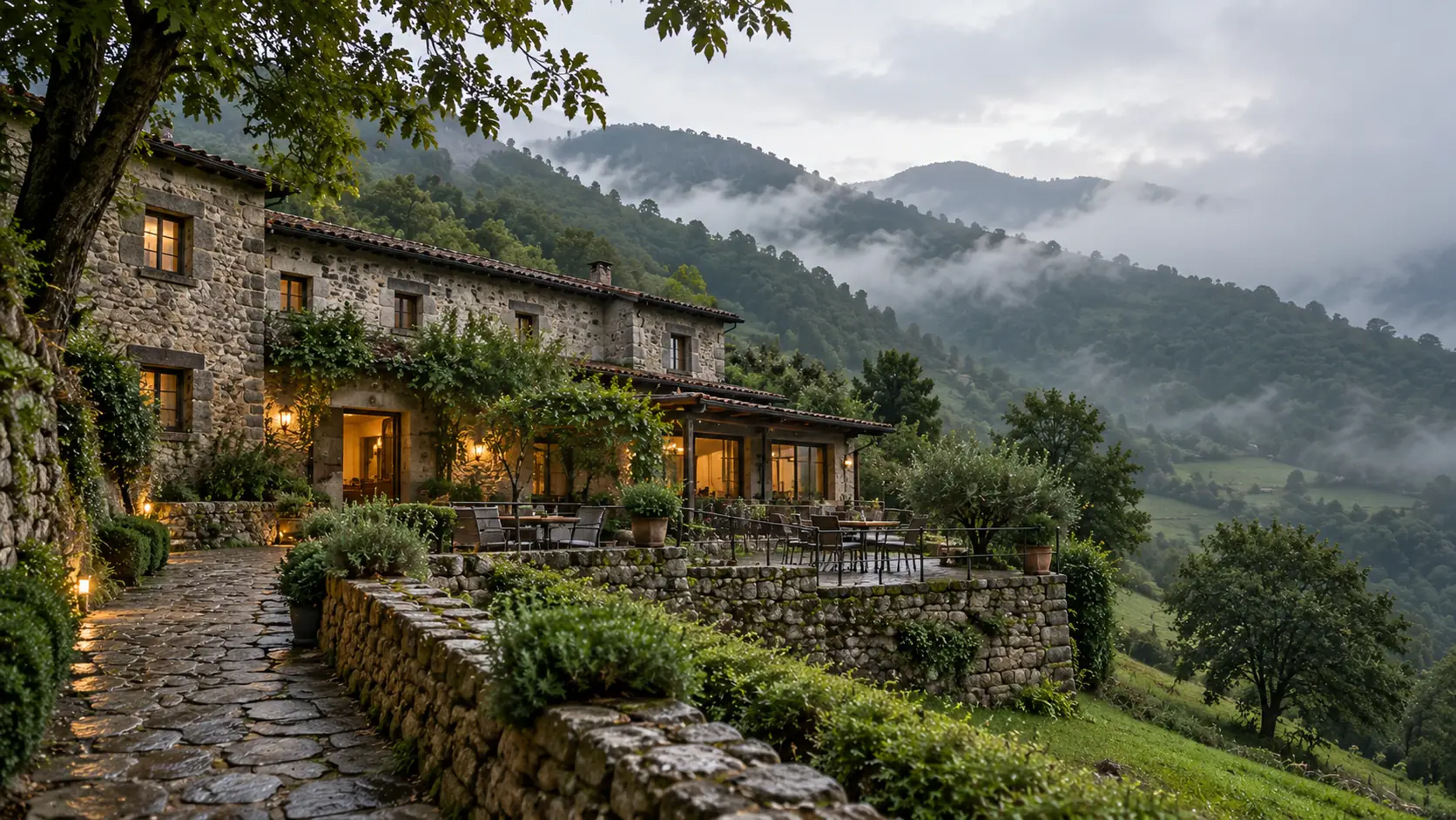 La casa de piedra entre la niebla, con la sierra detrás.